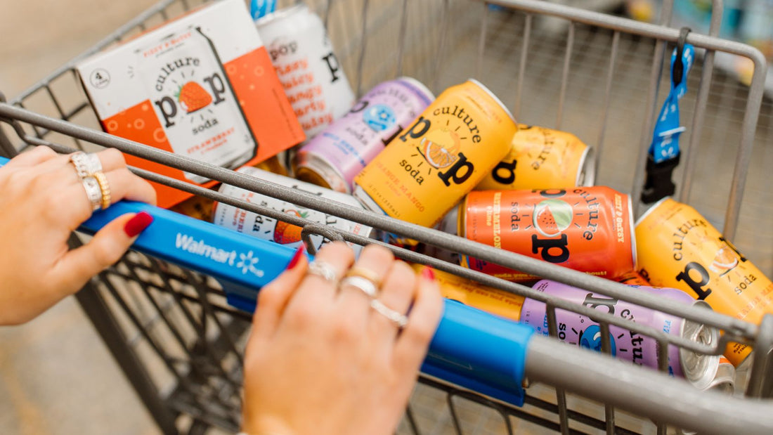 A shopping cart filled with colorful cans of culture pop soda and a 4pk carton of culture pop soda