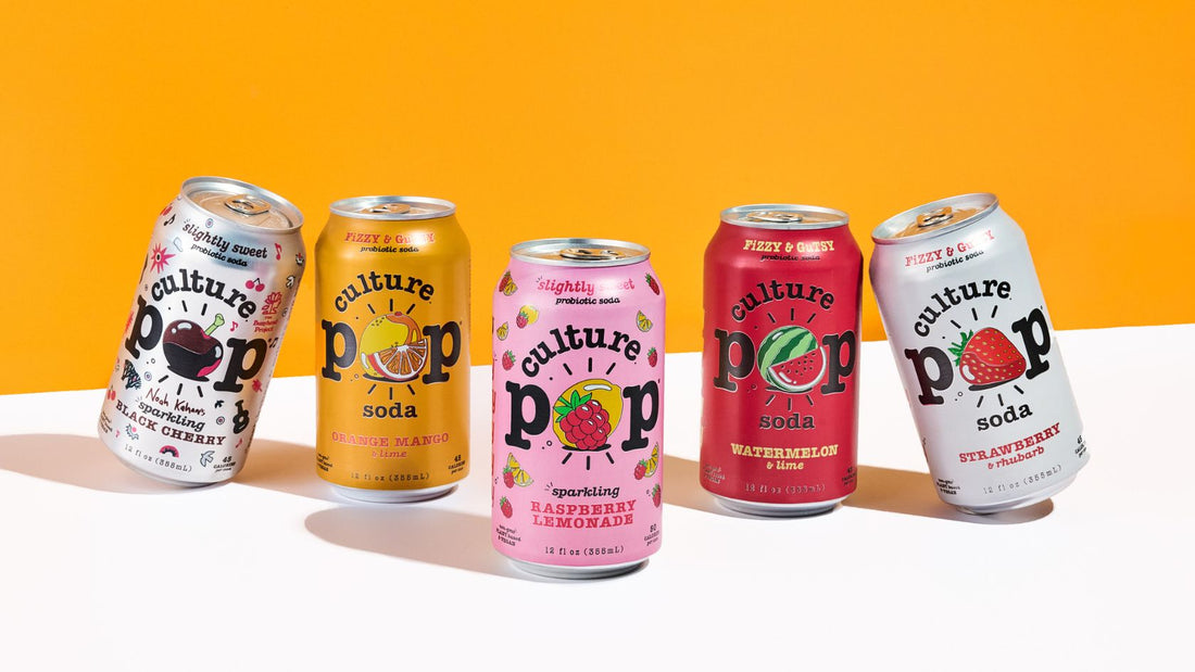 5 cans of culture pop soda on an orange background - colorful cans