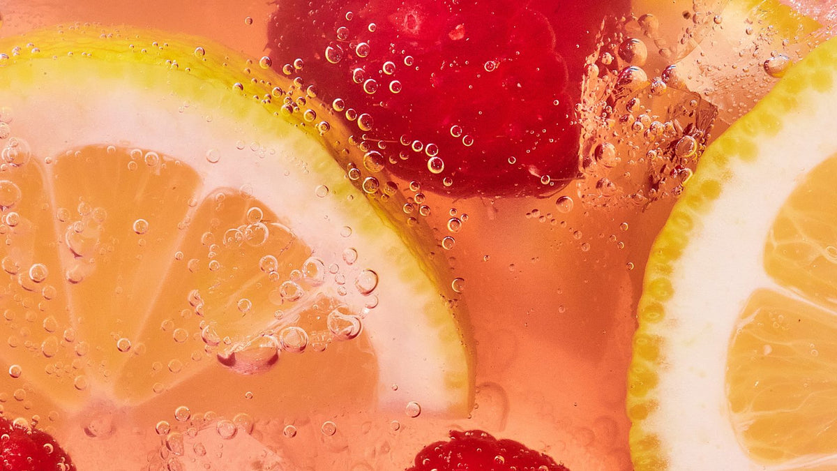 close up macro shot of lemon slices and raspberry in pink liquid