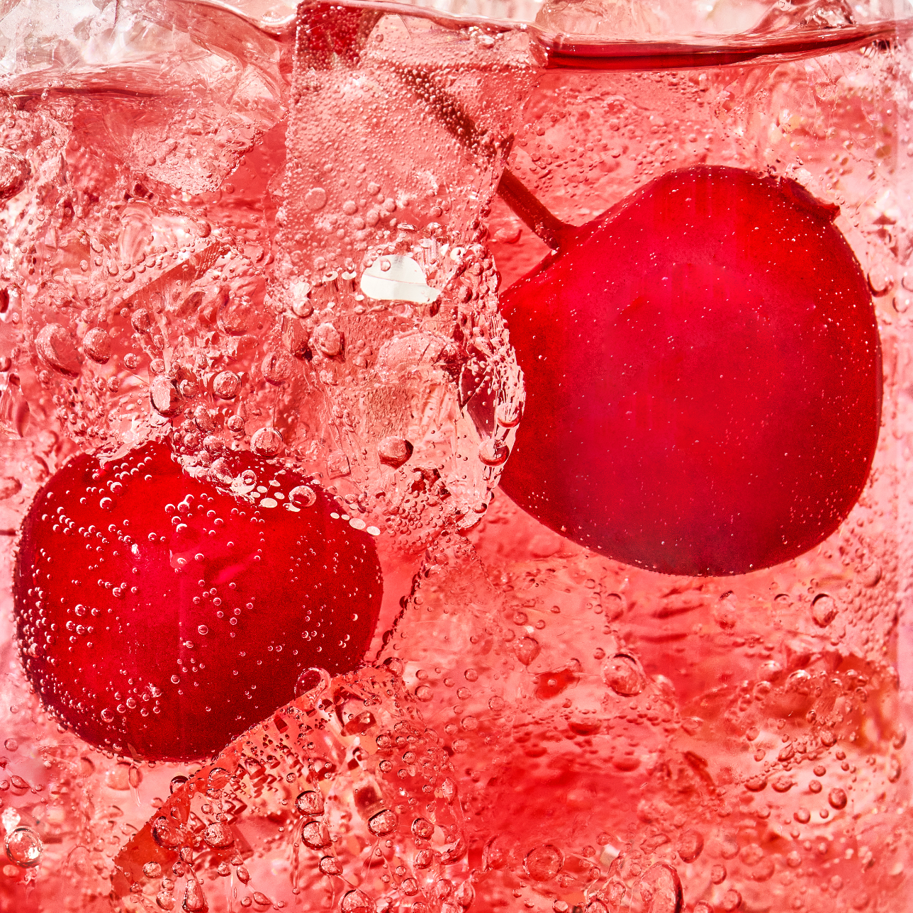 Close-up of cherries in a red liquid with ice cubes