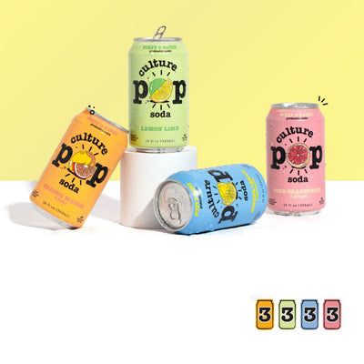 Four cans of Culture Pop soda in different flavors on a white surface with a yellow background.